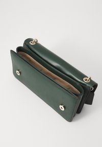 Green leather handbag with a smooth texture, featuring a flap closure, gold hardware accents, and a beige lined interior.