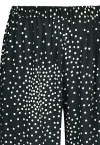 Czarne spodnie z wzorem w kropki w kolorze białym. Miękka tkanina z elastycznym pasem dla komfortu. Szerokie, luźne nogawki dla swobody ruchów.