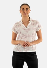 Blusa bianca con maniche corte a volant e scollo a V, caratterizzata da un delicato motivo floreale rosa. Tessuto leggero.