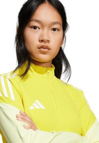 Heldere gele zip-up sportjack met witte strepen en logo-detail, met een aansluitend ontwerp en een gladde, lichtgewicht stof.
