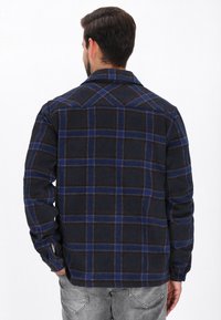 Zwarte geruite herenoverhemd met blauwe en rode strepen, met knoopmanchetten en een kraag. Gemaakt van een zachte, gestructureerde stof. Gezien van de achterkant.