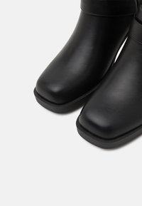 Mustad mustad nahast kingad, millel on ümar nina, sile pind ja lame kummitald. Diskreetne õmblusdetail varruka ääres.
