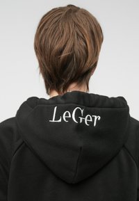 Μαύρη φούτερ μπλούζα με μαλακή υφή, διαθέτει κουκούλα με κορδόνι και το λογότυπο "LeGer" κεντημένο σε λευκό στην πλάτη.
