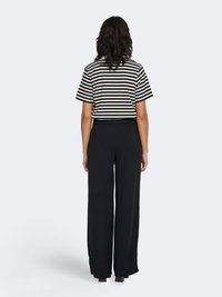 Pantalon large noir associé à un haut à manches courtes rayé noir et blanc. Présente une coupe décontractée et une texture de tissu douce.