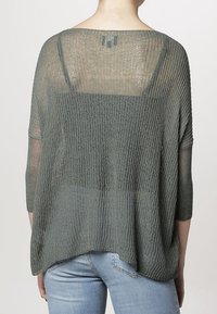 Sudadera de punto suelto y de gran tamaño en verde apagado con un escote ancho y mangas de tres cuartos. Tela texturizada con canalé horizontal.