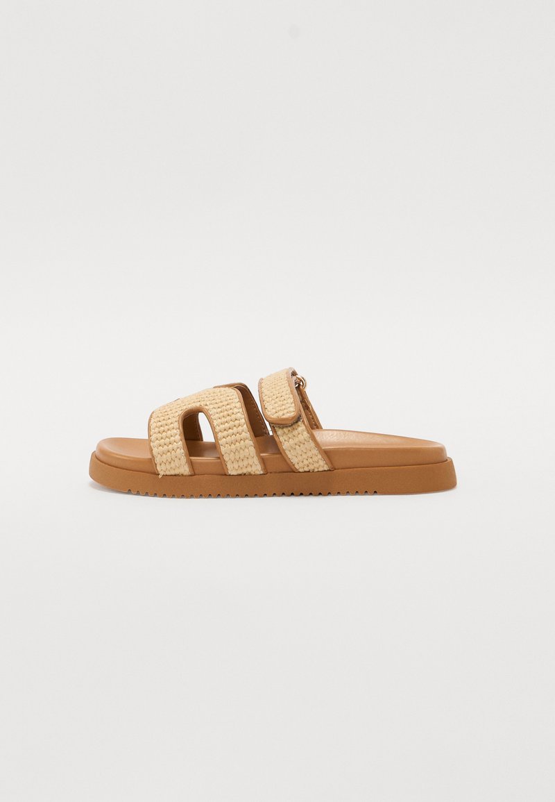 Beige woven slide sandal with two wide straps and a velcro closure. Features a cushioned sole and textured rubber outsole.