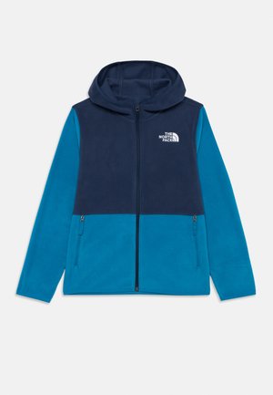 Veste en polaire avec capuche marine et partie supérieure, manches et bas en teal, fermeture éclair à l'avant, et logo The North Face sur la poitrine.