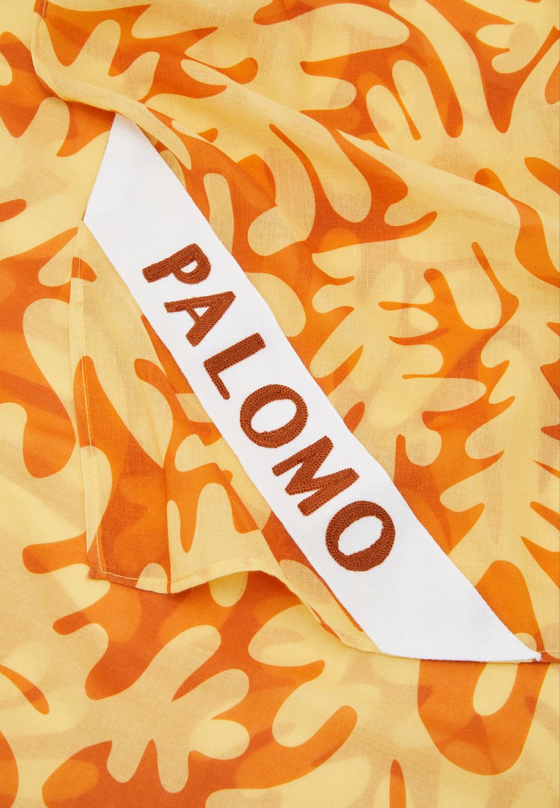 Yellow fabric with orange abstract patterns, featuring a white label with the word "PALOMO" in brown embroidery.