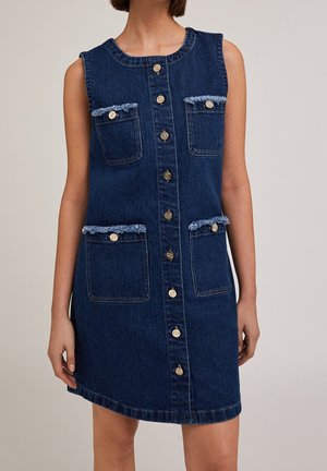 Mouwloze donkerblauwe denimjurk met knoopsluiting aan de voorkant en vier opgestikte zakken met rafelige afwerking en knopen.