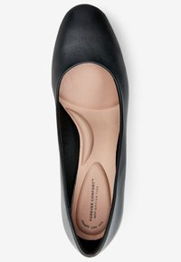 Scarpa piatta nera con esterno in pelle liscia, punta a mandorla e soletta imbottita beige con motivi a onda per un maggiore supporto.