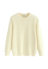 Pull-over en tricot couleur crème clair avec un motif gaufré texturé. Il présente un col rond ainsi que des poignets et un ourlet côtelés.