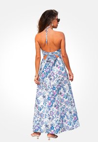 Kwiatowa sukienka maxi z niebieskimi, purpurowymi i białymi wzorami. Projekt na szyję, odkryty tył z wiązaniem, sięgająca do ziemi, lekki materiał.