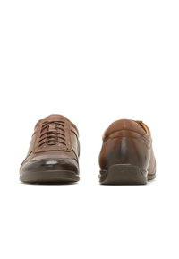 Brūni ādas apavi ar gludu apdari, ar auklām, noapaļotu pirkstu un zemu profilu gumijas zoli komfortam un stabilitātei.