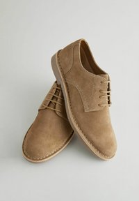 Brown suede shoes with a smooth texture, round toe, and lace-up design. Features subtle stitching details and a light rubber sole.