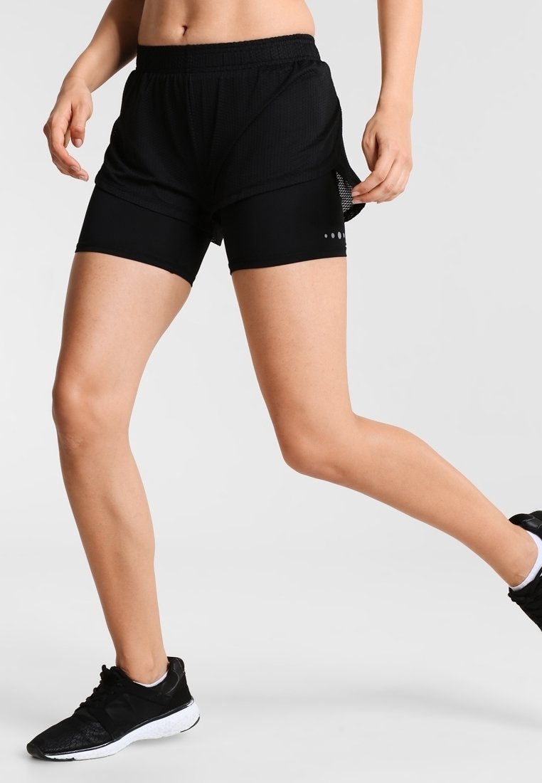 Pantalones cortos deportivos negros con una capa de malla, cintura elástica y detalles reflectantes con puntos. Diseñados para ofrecer comodidad y movilidad durante la actividad.