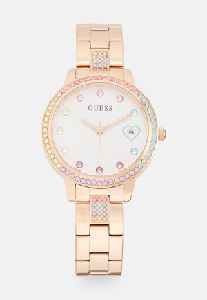 Roségoldene Uhr mit rundem Zifferblatt, kristallenen Akzenten in Pink und Blau sowie einem weißen Zifferblatt, das goldene Zeiger und ein herzförmiges Detail zeigt.