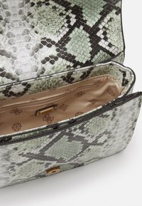 Kabelka z hadí kůže se zeleno-černým vzorem, strukturovaný design, magnetické zavírání a béžový saténový interiér s kapsou na zip.