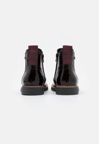 Sorte laklæder ankelstøvler med maroon stofdetaljer, sidelukninger, dekorativ broguing og robuste sorte gummisåler.