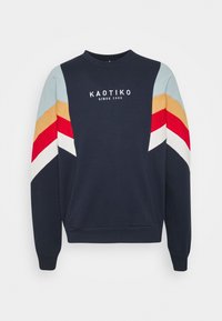 Felpa blu navy con maniche lunghe, caratterizzata da strisce diagonali colorate in rosso, giallo e azzurro, con dettagli bianchi. Logo stampato sul petto.