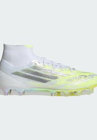 Ποδοσφαιρικά παπούτσια με λευκό και νέον κίτρινο συνθετικό επάνω μέρος, σχεδιασμό τύπου κάλτσας στον αστράγαλο και διάφανη πολύχρωμη σόλα με καρφιά. Ορατές ασημένιες λεπτομέρειες.