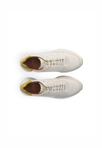 White leather sneakers with a rounded toe, yellow heel accent, and flat laces. The interior features a tan lining. Lightweight design.