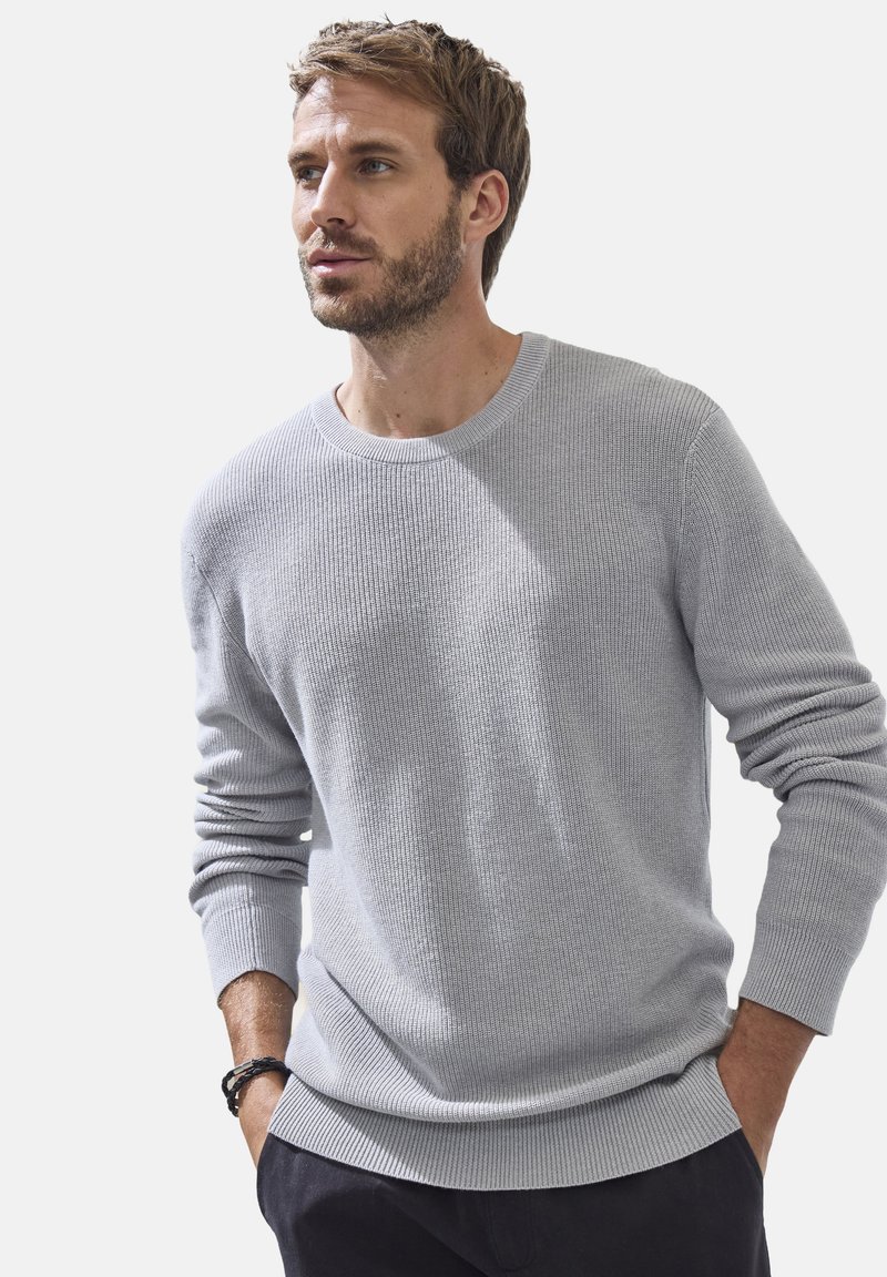 Helles graues, geripptes Strickoberteil mit rundem Hals und langen Ärmeln, das eine legere Passform und eine subtile Textur bietet. Lässiges Design.
