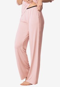 Jasnoróżowe spodnie piżamy wykonane z miękkiego materiału, charakteryzujące się luźnym krojem, elastycznym pasem i bocznymi kieszeniami oraz zwiewnym, szerokim fasonem.
