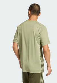 Camiseta deportiva de color verde oliva claro con mangas cortas y una tela suave que absorbe la humedad, con rayas laterales de color verde oscuro.