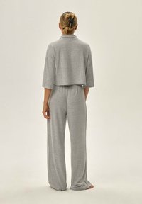 Szary zestaw piżamowy składający się z krótkiego topu i szerokich spodni. Miękka tkanina o gładkiej fakturze, charakteryzująca się luźnym krojem i delikatnym połyskiem.