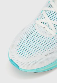 Scarpa da corsa bianca con tomaia in mesh caratterizzata da accenti turchesi e un design testurizzato. Chiusura con lacci per una calzata sicura.