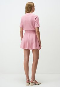 Set due maglia rosa composto da un top aderente con maniche corte e una gonna a ruota. Tessuto liscio, lunghezza sopra il ginocchio.