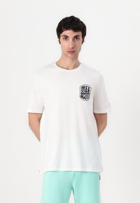 T-shirt de algodão branco com mangas curtas, gola redonda e um logótipo bordado a preto no lado esquerdo do peito. Textura suave, corte descontraído.