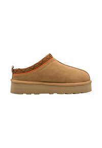 Chaussure slip-on en suède marron avec une semelle épaisse beige, présentant un accent géométrique orange au niveau du col et un tirant à l'arrière.
