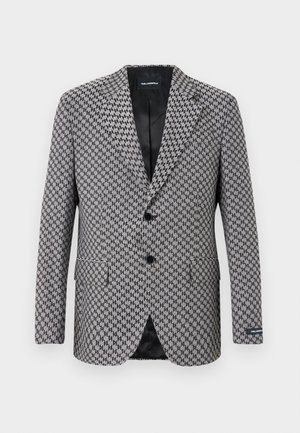 Hall houndstooth rõivastekk, kahe nööbiga sulgemisega, lõiketeedega krae ja kaks esikotti. Sisemine must vooder, mis on valmistatud tekstuuriga kangast.