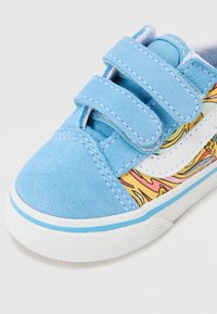 Blå ruskinn sneakers med borrelåsremmer, med et fargerikt grafisk mønster på siden, hvite detaljer og en teksturert gummisåle.