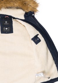 Navy outdoor jacket with faux fur hood. Cream interior lining, featuring a label and an audio cable pocket with subtle hardware details.
