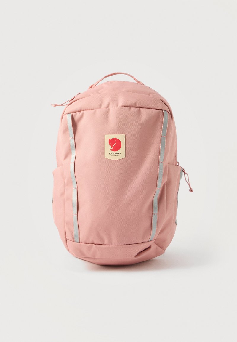 Zaino Fjällräven rosa con due strisce riflettenti verticali, manico superiore, tasche laterali e toppa con logo al centro davanti.