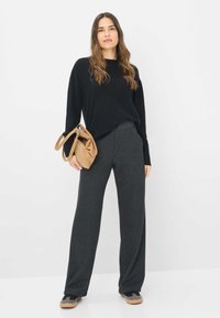 Zwarte langmouwtrui gecombineerd met donkergrijze wijde broek en een bruine suède handtas. Dit outfit heeft een casual, losse pasvorm en neutrale kleuren.