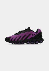 Ljubičaste i crne sportske tenisice s crnim vezicama, crnim potplatom koji sadrži okrugle ljubičaste zračne jastučiće i crnim Nike swoosh logotipom.
