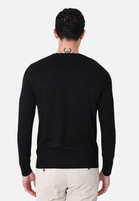 Maglione nero lavorato a maglia con maniche lunghe, scollo rotondo e orlo a coste. Il tessuto appare morbido e strutturato, adatto per un abbigliamento casual.