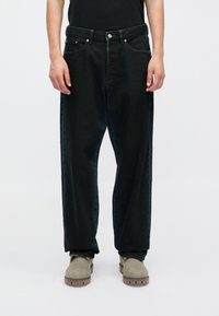 Črne kavbojske hlače z ohlapnim krojem, petimi žepi in srebrnimi dodatki. Tekstura je gladka, z rahlim izblidkom in detajli šivov.