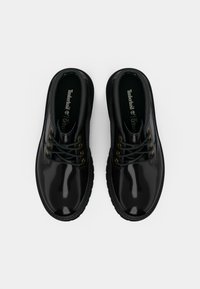 Scarpe Oxford in pelle nera con finitura lucida, lacci verdi, occhielli in tono oro e suola in gomma testurizzata. Inclusi plantari Ortholite.