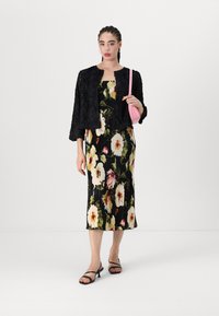 Black textured jacket paired with a floral print, pleated midi dress featuring white, yellow, and red flowers, complemented by black sandals and pink bag.