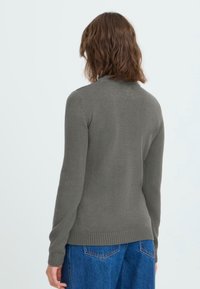 Gray knitted sweater with a crew neckline, fitted long sleeves, and ribbed hem. Worn with high-waisted blue denim jeans.