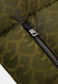 Olive green puffer fabric with a subtle geometric pattern, featuring a black zipper and metal pull tab for secure closure.