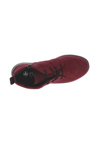 Zapato de ante burdeos con diseño de cordones, suela plana negra y detalle de cremallera en el lateral. El interior presenta un logotipo en una plantilla negra.