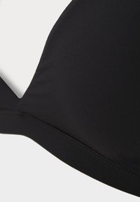 Haut de bikini noir en tissu doux avec une texture lisse, des bonnets triangulaires et un design simple sans motifs ni accents supplémentaires.