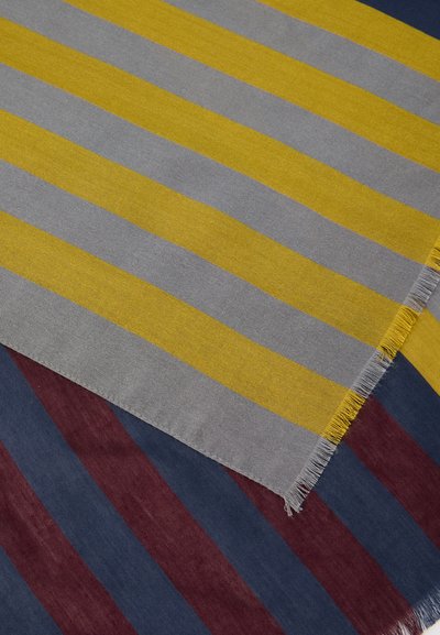 Δύο επικαλυπτόμενα υφάσματα με ρίγες: το ένα με κίτρινες και γκρι ρίγες, το άλλο με ρίγες σε ναυτικό μπλε και μαρόν, και τα δύο με  fringing κρόσσια στις άκρες.