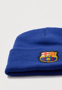 Gorro beanie de punto azul con el logo bordado del FC Barcelona, decorado con rayas rojas y amarillas, un balón de fútbol y contornos en negro.