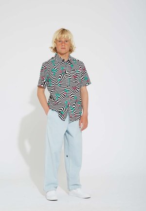 Kurzarmhemd mit einem schwarz-weißen, gewellten Streifenmuster und pinken sowie grünen Blumenakzenten, kombiniert mit hellblauen Hosen.